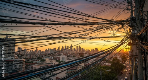 Urban sunset viewed through a tangled mass of electrical wires and cables above a cityscape