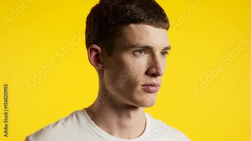 Young man, serious expression, yellow backdrop