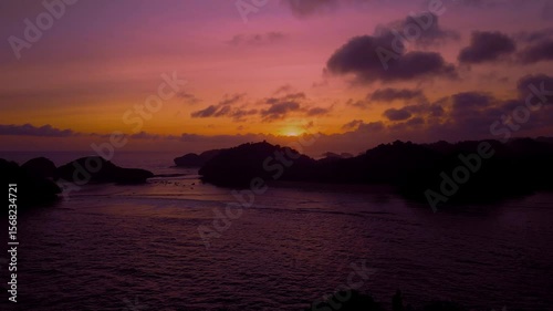 Aerial view of sunset silhouette from ocean cliff.