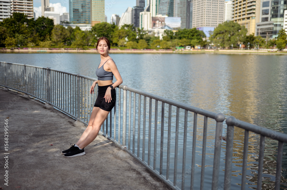 Obraz premium Woman Enjoying a Sunny Day by the Lakeside in an Urban Setting, Showcasing Fitness and Wellness