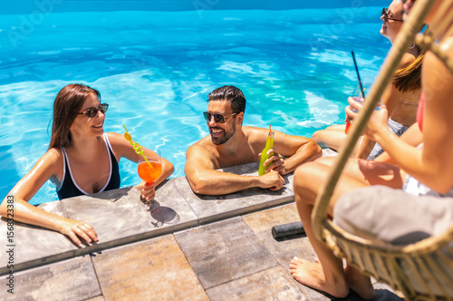 Group of Young People Hanging Out and Drinking Cocktails by the Pool