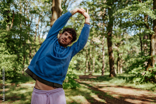 Wallpaper Mural Young man stretching arms in wooded park during workout Torontodigital.ca