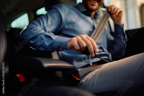 Close up of driver fastening seatbelt in car.