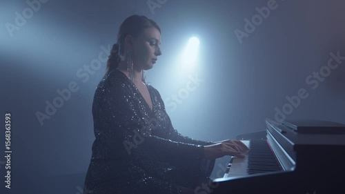 Pianist plays the piano in dark room with smoke and spotlights. Female practicing playing the piano. Pianist on stage. Cinematic video. 4K, UHD