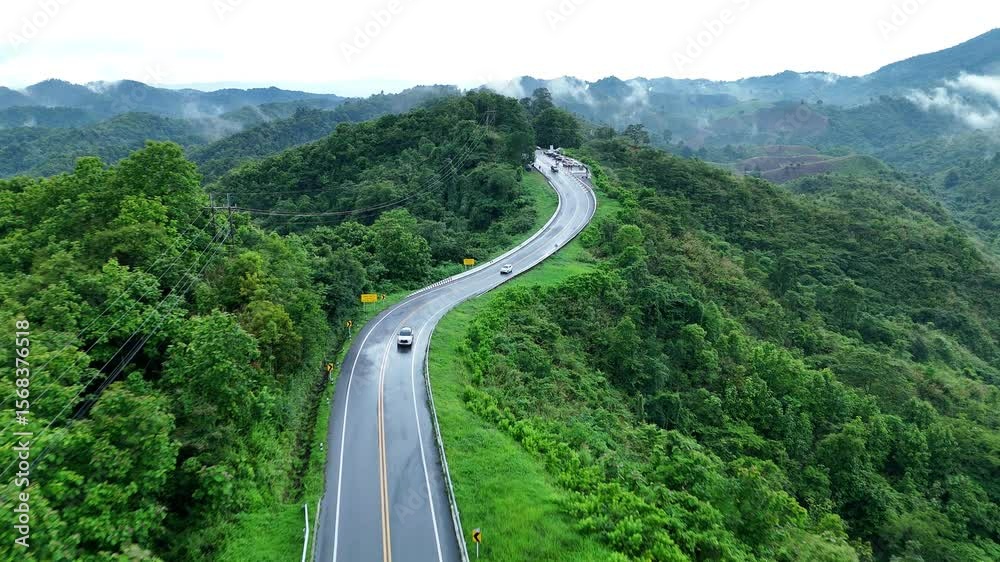 Aerial view of car driving on country road in forest. Cinematic drone shot flying over country road with curved in the mountain. Aerial view of car driving on country road in forest. Cinematic drone shot flying over country road with curved in the mountain.
