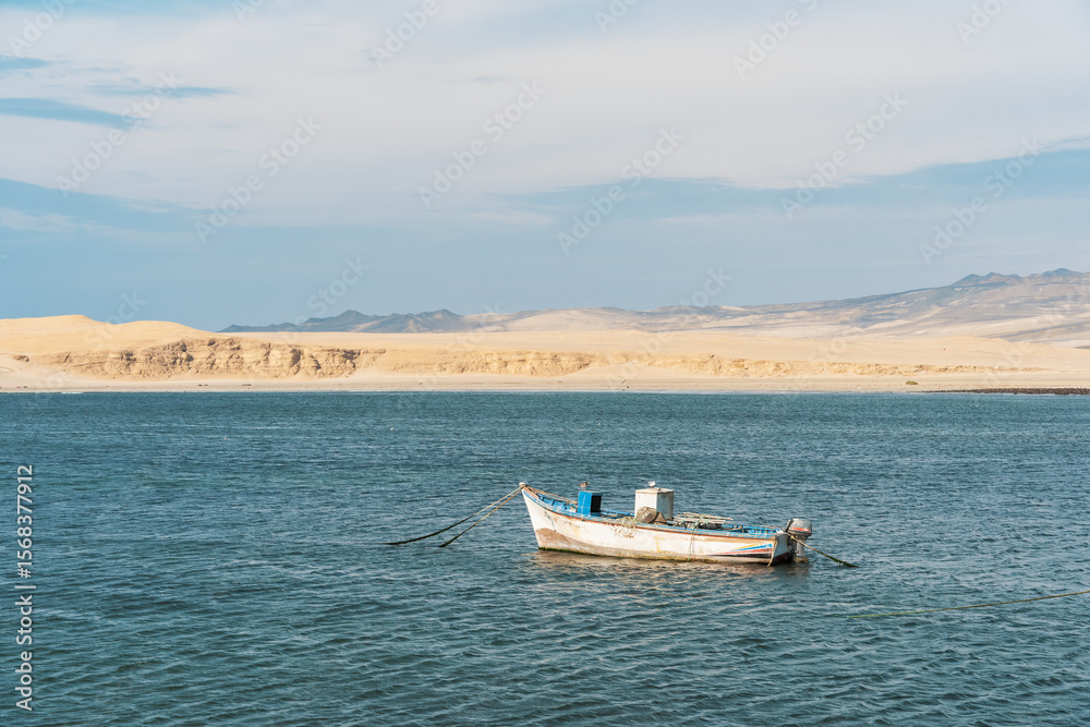 Obraz premium A tranquil scene with a fishing boat floating in the calm waters of Pacific Ocean at Paracas National Reserve, Peru.