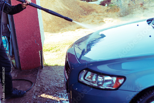 Car washing with high-pressure water spray at an outdoor facility on a sunny day