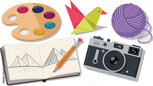 Composition of art supplies including paint palette camera origami and sketch book