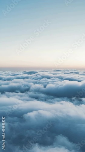 Flight above the clouds view with soft blue and white hues, aerial perspective. Flight above the clouds gives dreamy ethereal look as sunlight peeks through the cloudscape.