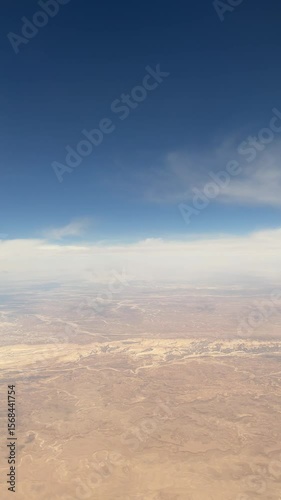 Aerial view of vast arid landscape showcasing rugged terrain, layered rock formations, and expansive sky, highlighting the natural beauty and geological diversity of remote wilderness areas
