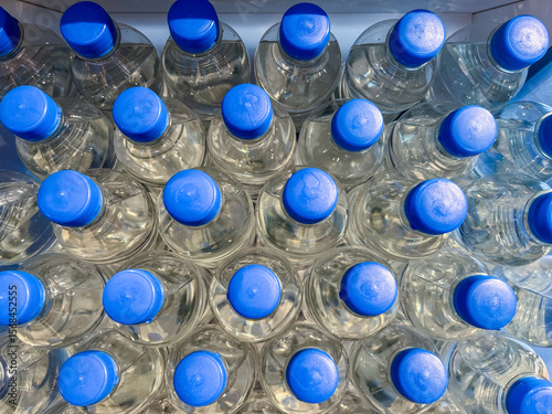 Foto Top view of numerous clear plastic water bottles with blue caps arranged neatly