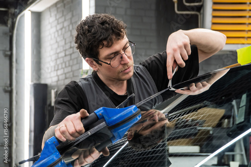 Automobile special workers replacing windscreen or windshield of a car in auto service station garage. Glass of the car, removed with the help of professional suction cups. The process of car repair. 
