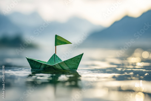 Handmade paper boat sailing on tranquil waters with scenic mountain backdrop