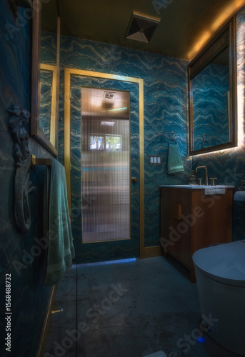 Moody ocean-themed bathroom with custom wave wallpaper, gold trim, and dramatic lighting—featuring a cinematic view of the door framed in opulent detail and aquatic-inspired texture.