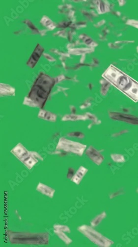 us dollar bills tumble and rain down against a bright green screen background with an upward perspective concept of money falling