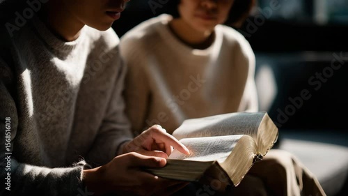 A close-up of two young people reading together, with warm tones and soft lighting