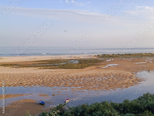 Boats in the Ria Formosa at low tide at sunset and paragliding over the sea at Cacela Velha beach, Algarve PORTUGAL
