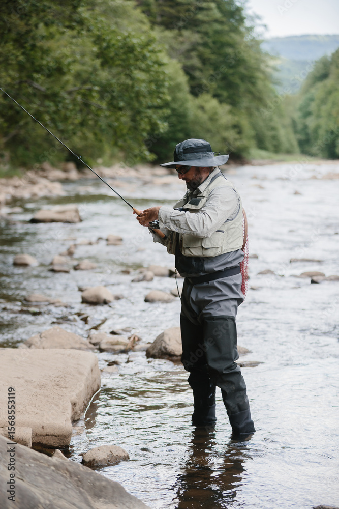 Fisherman wading in river casting line with fly fishing rod Fisherman wading in river casting line with fly fishing rod
