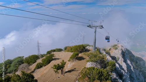 Time lapse: cable car cabins moving fast high above mountain slopes and white clouds at Mount Babadag in Mugla, Turkey. Aerial rope transit, gondola lift. Timelapse and transportation concept