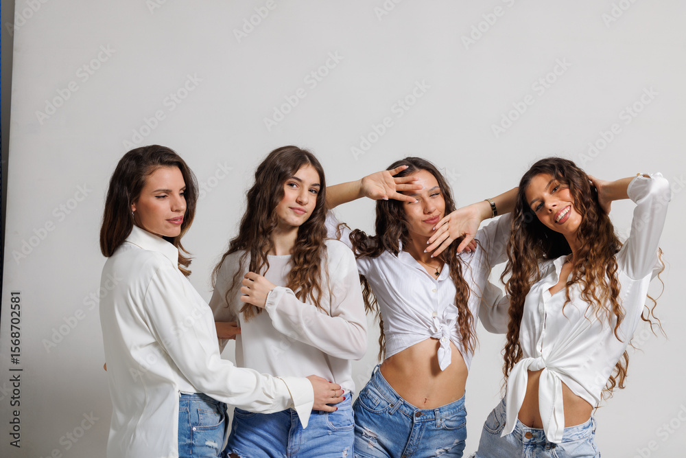 Four women posing together for a cheerful group portrait in casual outfits Four women posing together for a cheerful group portrait in casual outfits