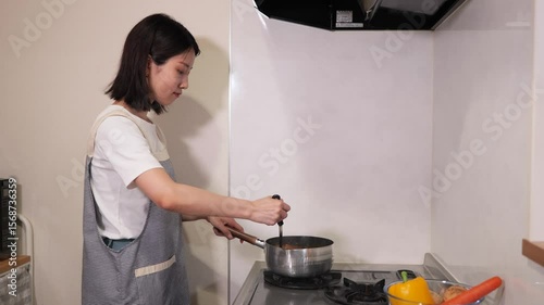 鍋を混ぜながら料理をする女性