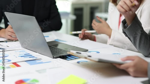 Business people analyzing statistics, charts and graphs on documents and laptop.