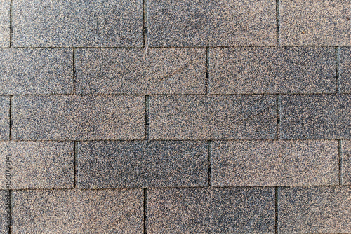 asphalt roof shingles, exhibiting a weathered, granular texture and varying shades of gray and brown, ideal for exterior design and architectural themes.
