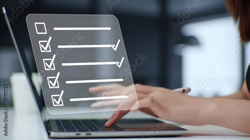 Woman Completing Digital Checklist On Laptop In Blurred Office Environment Using Stylus For Efficient Task Management And Project Tracking