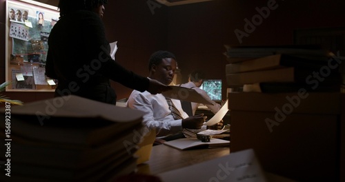 Working in a police office. A woman brings folders with documents to her colleagues