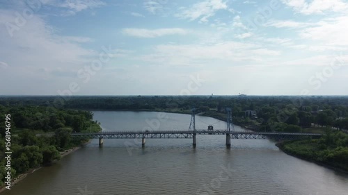 Wallpaper Mural Aerial drone panning shot of a truss bridge with traffic, spanning a wide river in a lush, forested landscape. Torontodigital.ca