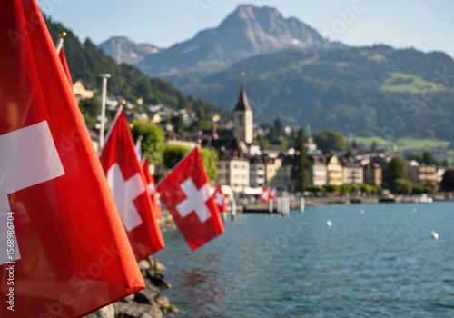 Swiss flags lining a calm lake promenade with distant snow-capped mountains and a picturesque town, representing national pride. Swiss National Day background for greeting card or banner.	
