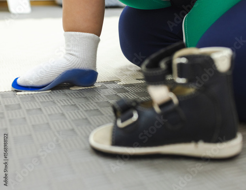 Orthopedist tries on individual orthopedic insoles and shoes for the child's foot to prevent foot deformities, close-up