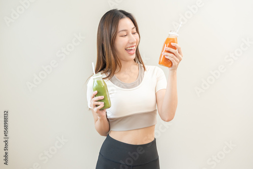 Orange, green detox juice, smile asian young woman hand holding bottle of vegetable juice, carrot smoothie for diet, girl drinking healthy meal food for weight loss, standing isolated on background