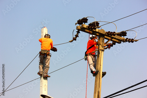 the electric worker are installing high voltage line on pole. workers put on safety belt helmet climb electric pole and work with caution
