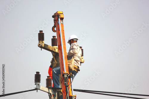 the electric worker are installing high voltage line on pole. workers put on safety belt helmet climb electric pole and work with caution
