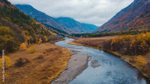 Majestic river flows through autumn valley showcasing vibrant foliage and serene landscape in mountain terrain