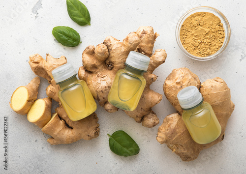 Bottles of immune ginger energy shot drink on top of fresh raw ginger root to light background.Macro.