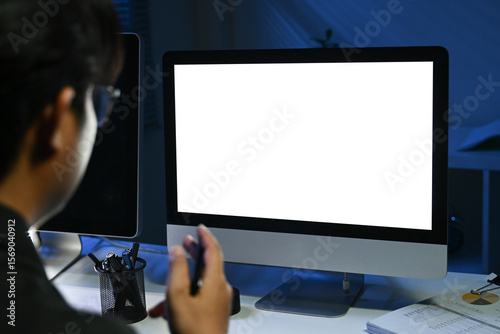 Fotografía A man is sitting in front of a computer monitor with a black background