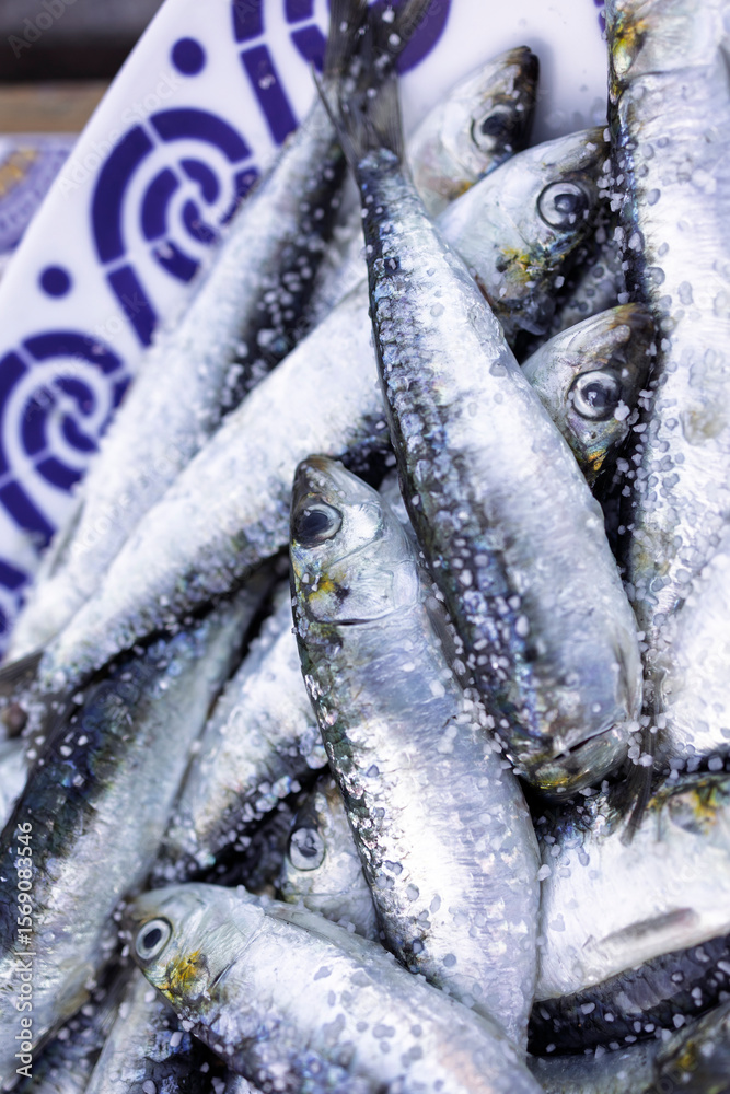 Obraz premium Fresh sardines sprinkled with coarse salt on a decorative plate