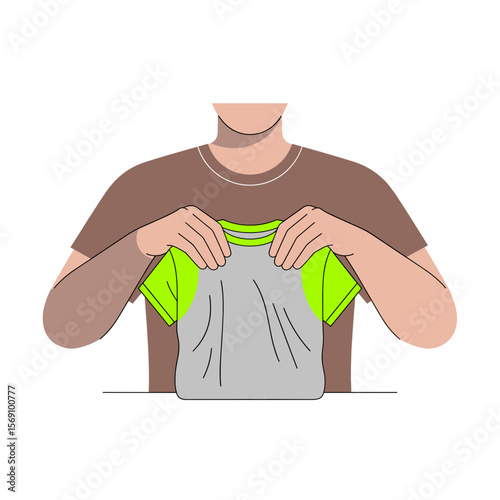 Man folding a gray t-shirt with green accents at a table  