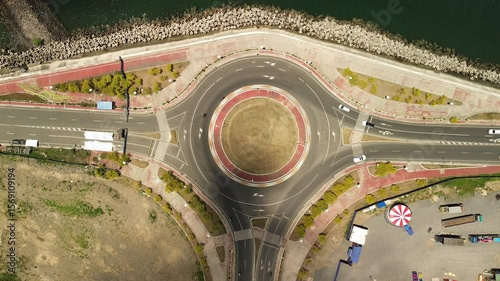 Wallpaper Mural Stationary drone shows a perfect circle interchange beside Davao City's shoreline; grey asphalt, red curb and faded grass contrast with teal seawater beyond the breakwater. Torontodigital.ca