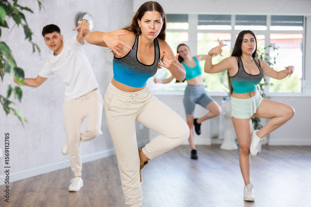 Fototapeta premium Group of positive teenagers dancing modern dance in ballroom.