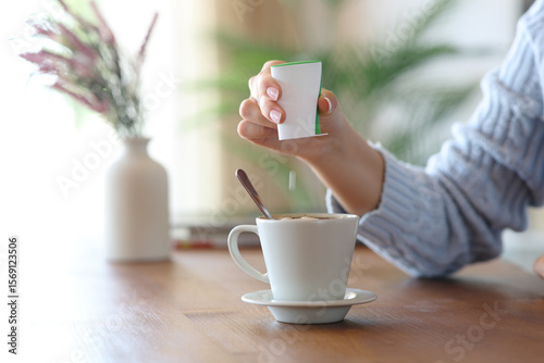 Schilderij op canvas Woman hand throwing saccharin pill on coffee cup at home
