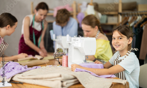 Schilderij op canvas Girl child sews during practical lesson at school of young fashion designers and tailors