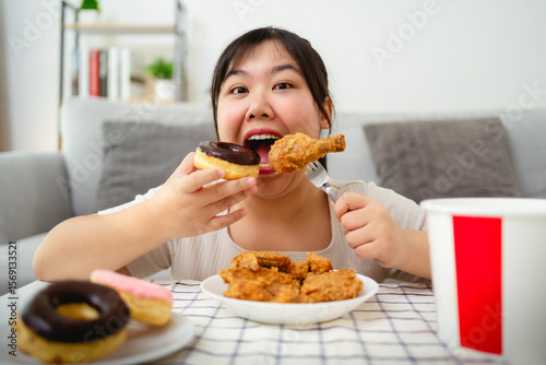 Asian young woman happily eating fried chicken and donuts, unhealthy food, junk food, weight gain