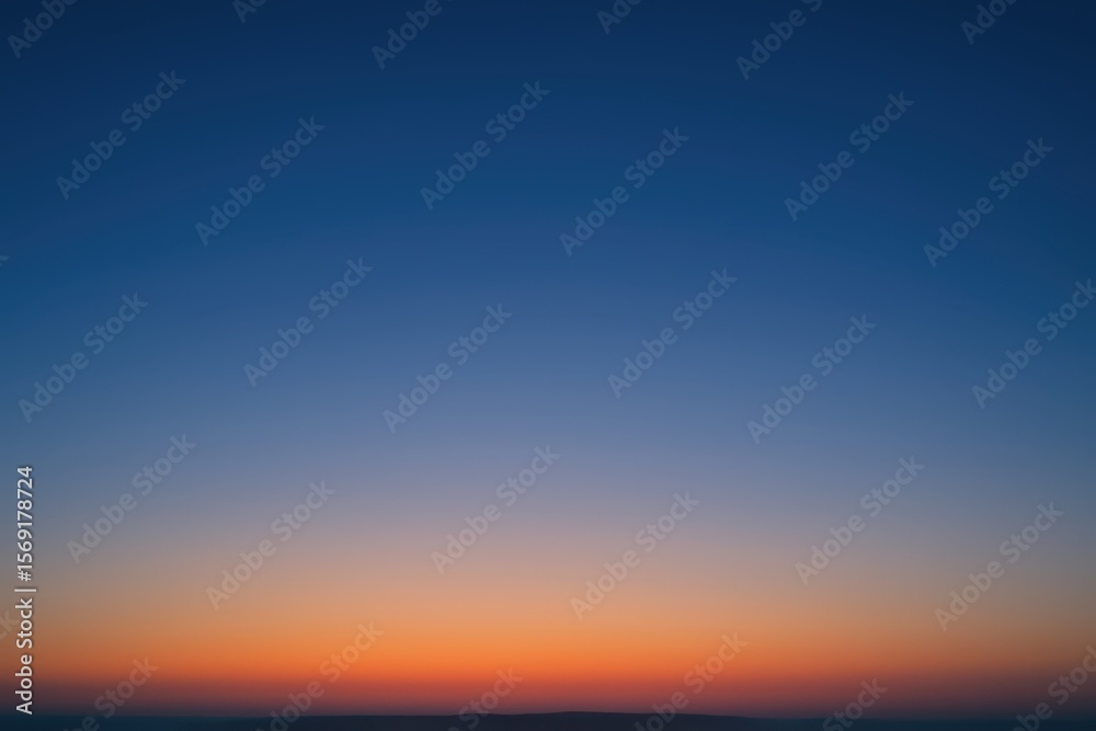 Fototapeta premium Vibrant orange and pink sunset sky gradient over a distant dark horizon