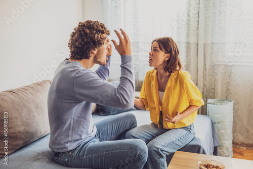 Man and woman are sitting at sofa and arguing. Relationship problems.