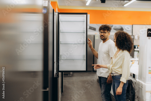 Couple Examining Refrigerator in Electronics Store for Home Appliance Purchase