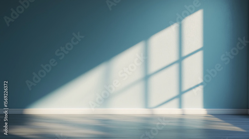 Sunlight casts a grid shadow through a window onto a smooth floor and teal wall in an empty, minimalist room.