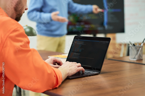 Fotografie Caucasian man in orange prison uniform using laptop during classroom lesson, ins